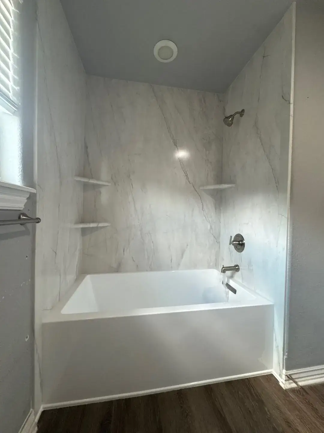 Tub replacement with a white marble-look wall surround