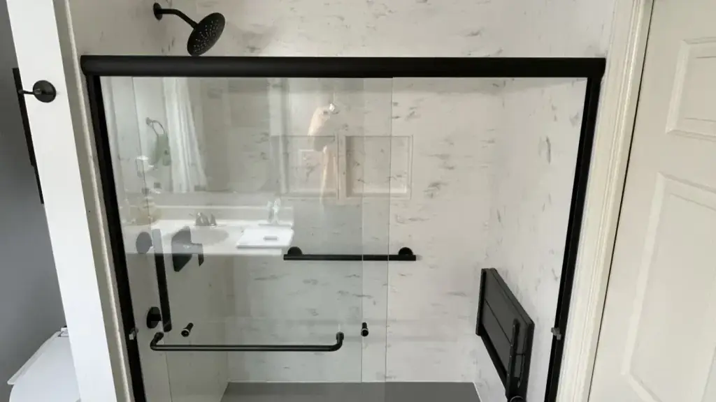 Bentonville tub-to-shower conversion with a black slider, a fold-down seat and a grab bar