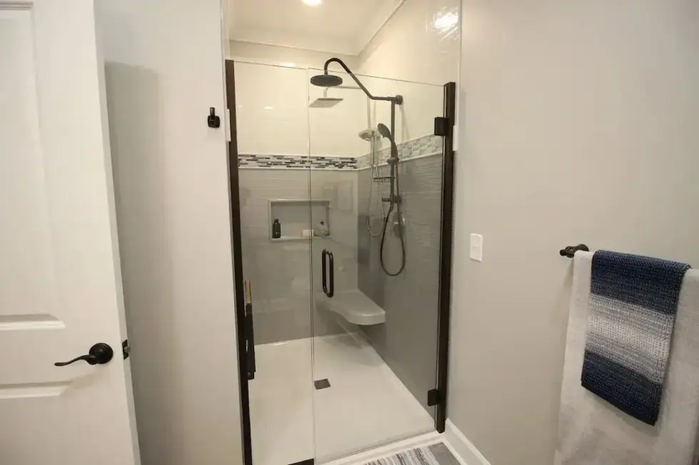 Black-trim glass shower with a mosaic band and a wall niche