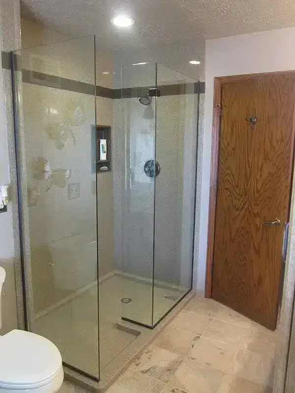 Frameless corner shower in a bathroom with a wood door