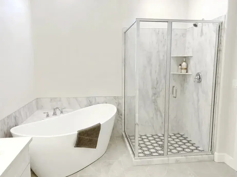 Freestanding tub beside a framed corner shower with a hexagon mosaic floor