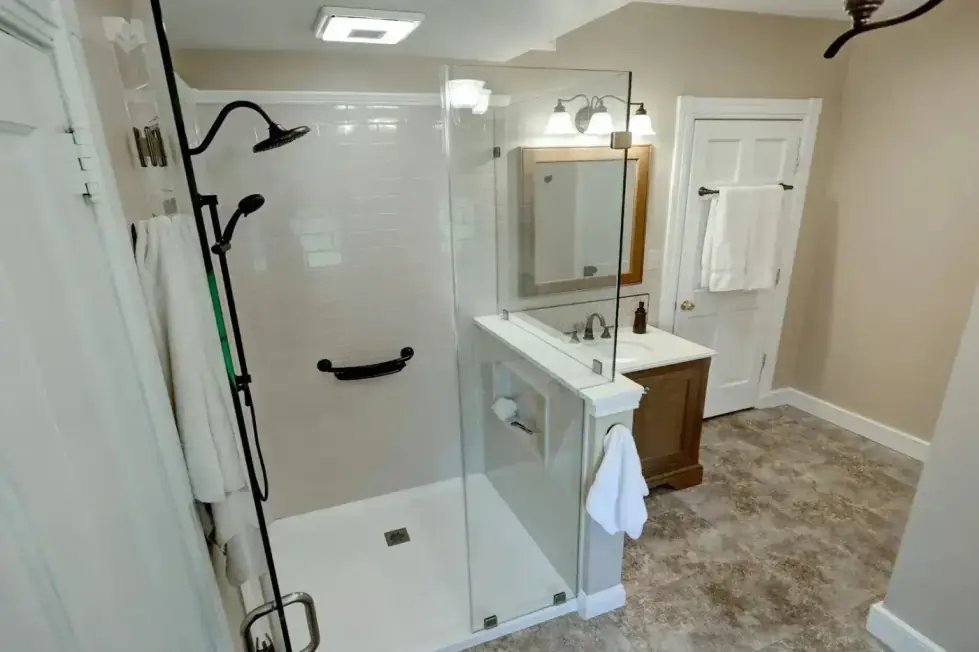 Pony-wall walk-in shower with a glass panel above the half wall, black fixtures and a grab bar