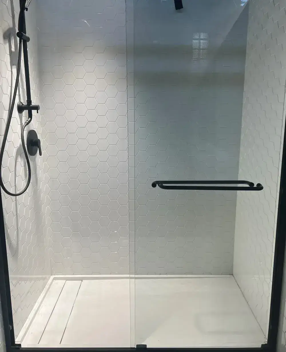 Tub-to-shower conversion in Lowell with white hexagon wall panels and matte black hardware