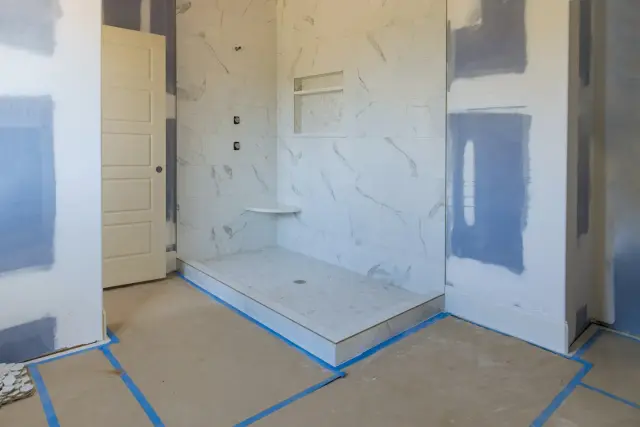 A bathroom mid-install with the base set, floor taped off and wall panels going up
