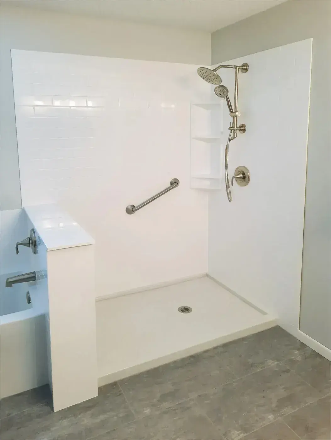 White walk-in shower base with a low threshold, a grab bar and a corner caddy