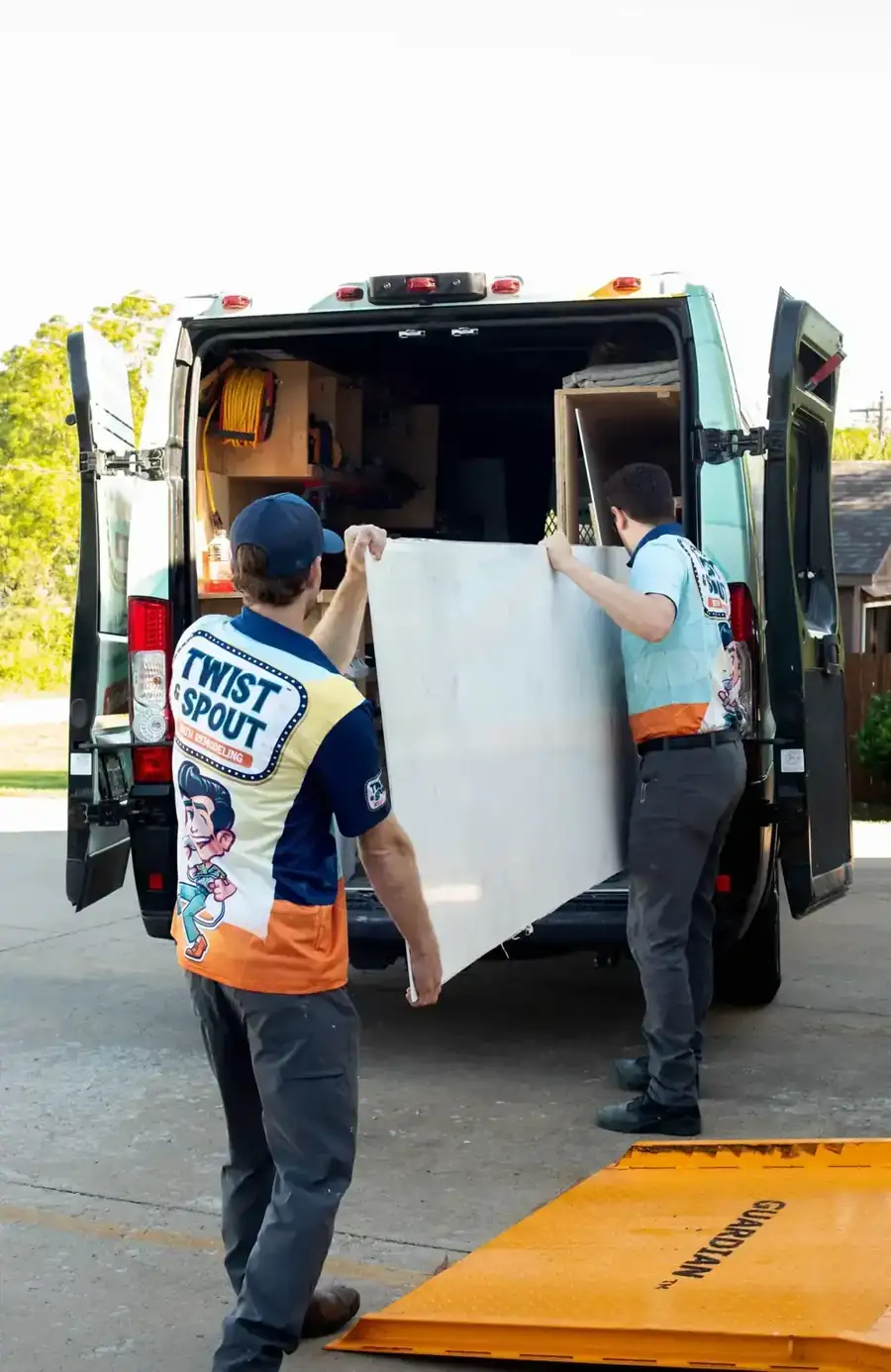 Two Twist & Spout crew members carrying a large wall panel out of a company van